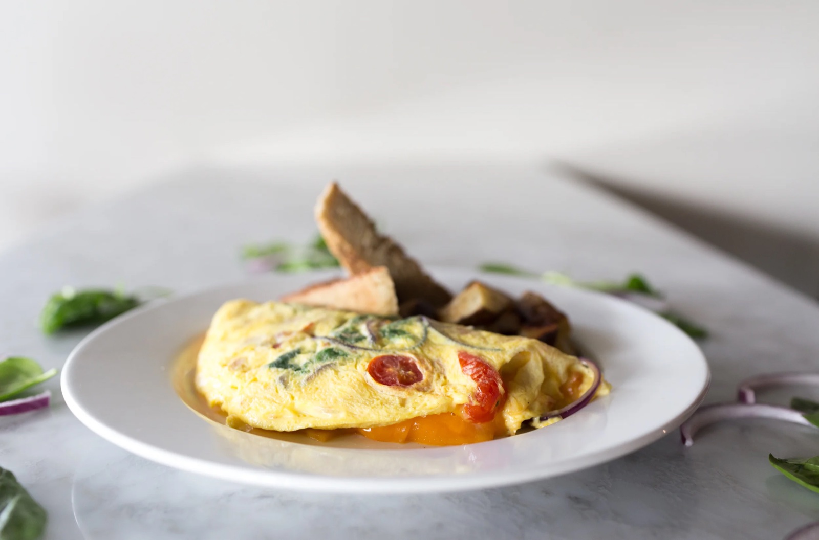 A folded veggie omelette with spinach and tomato, toast on the side.