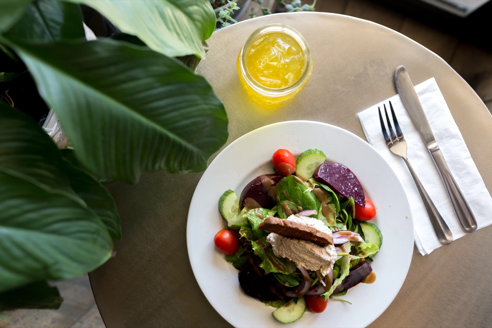 An overhead beet-and-greens salad with walnut ricotta and an iced tea.